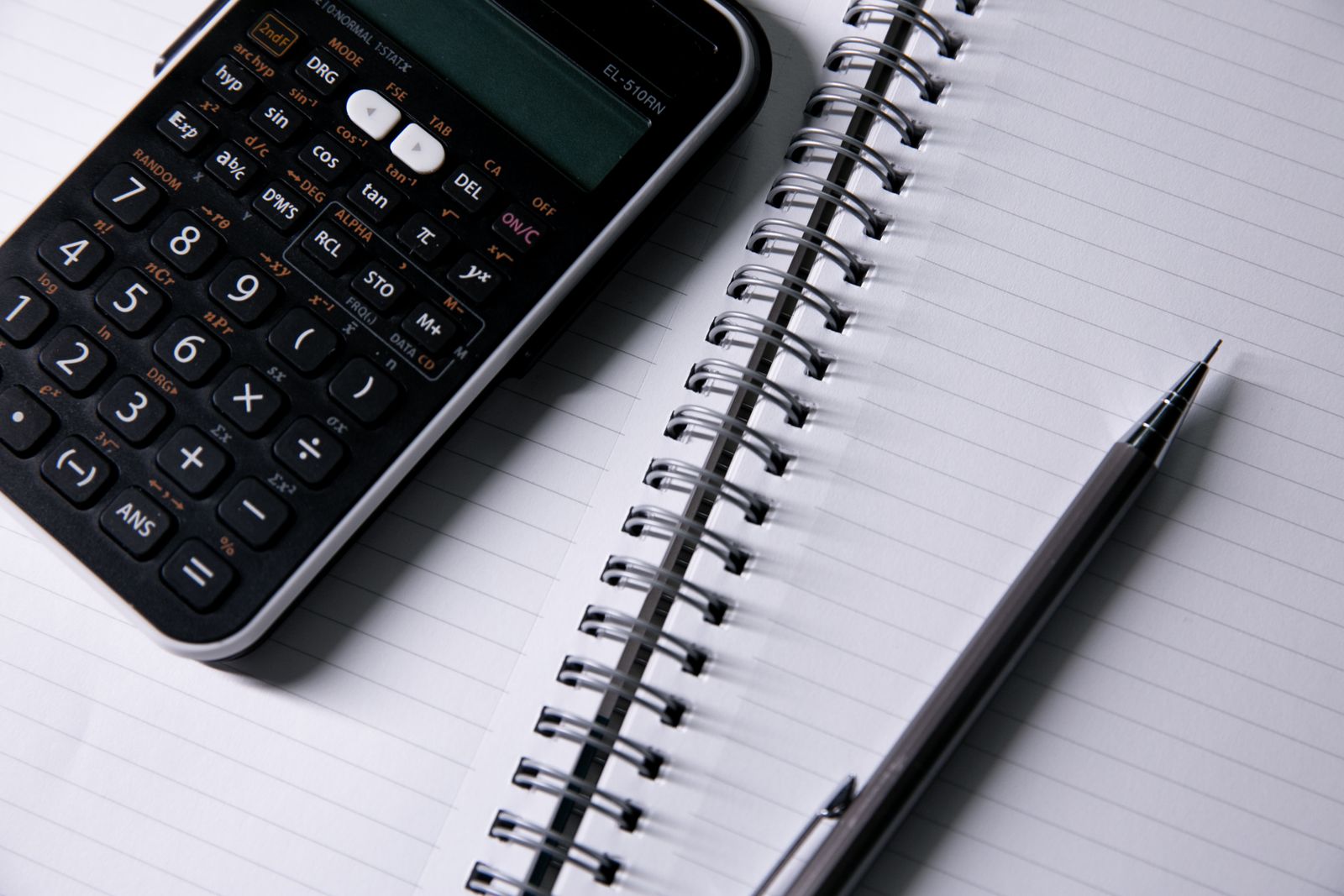 Calculator, open notebook and pen used to compare plan costs